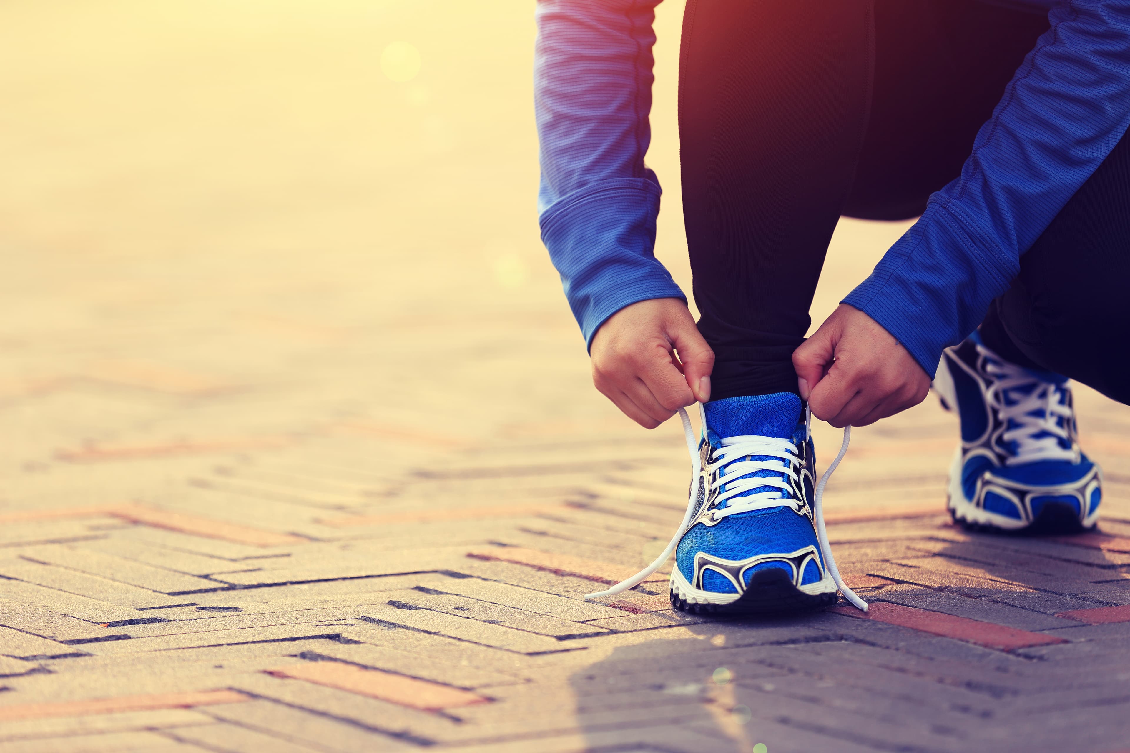 young woman runner tying shoelaces on city road