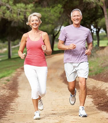 Senior couple running in park