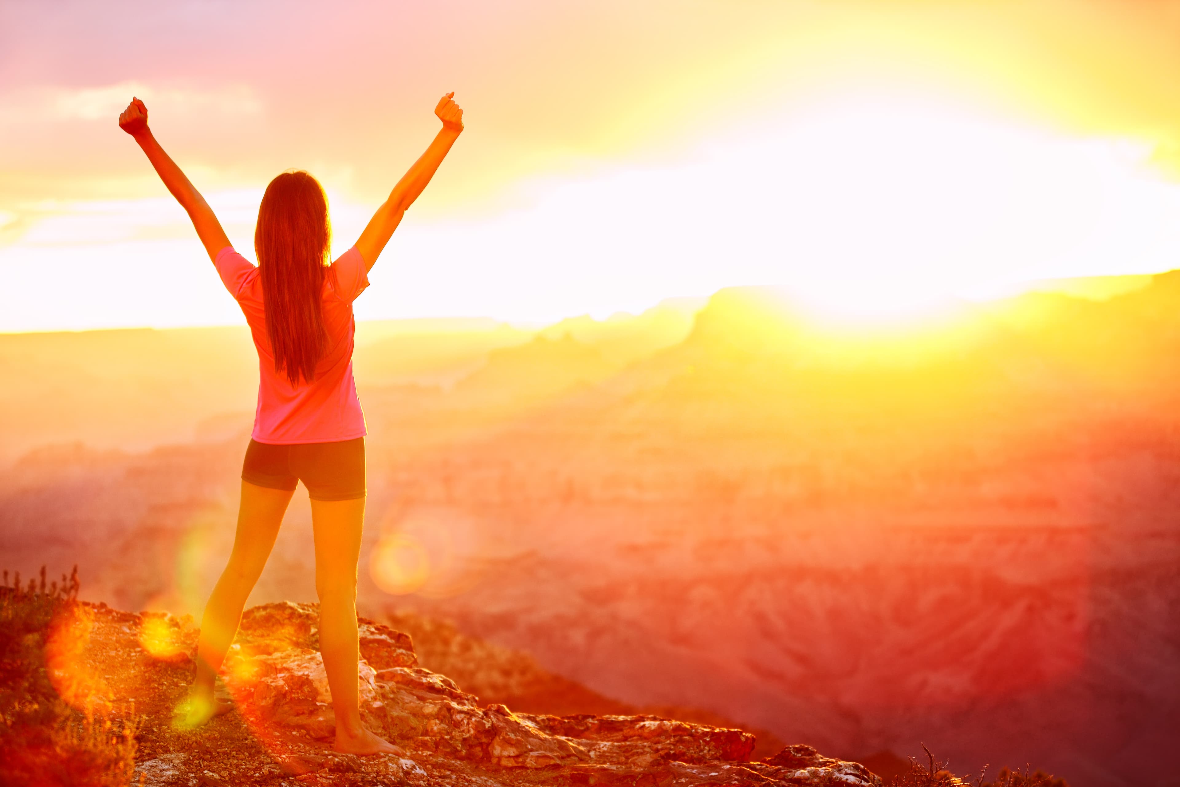 Freedom and adventure - woman happy in Grand Canyon. Free cheering girl with arms raised enjoying serene sunset in winning pose with arms stretched after hiking. Female model in Grand Canyon, USA.