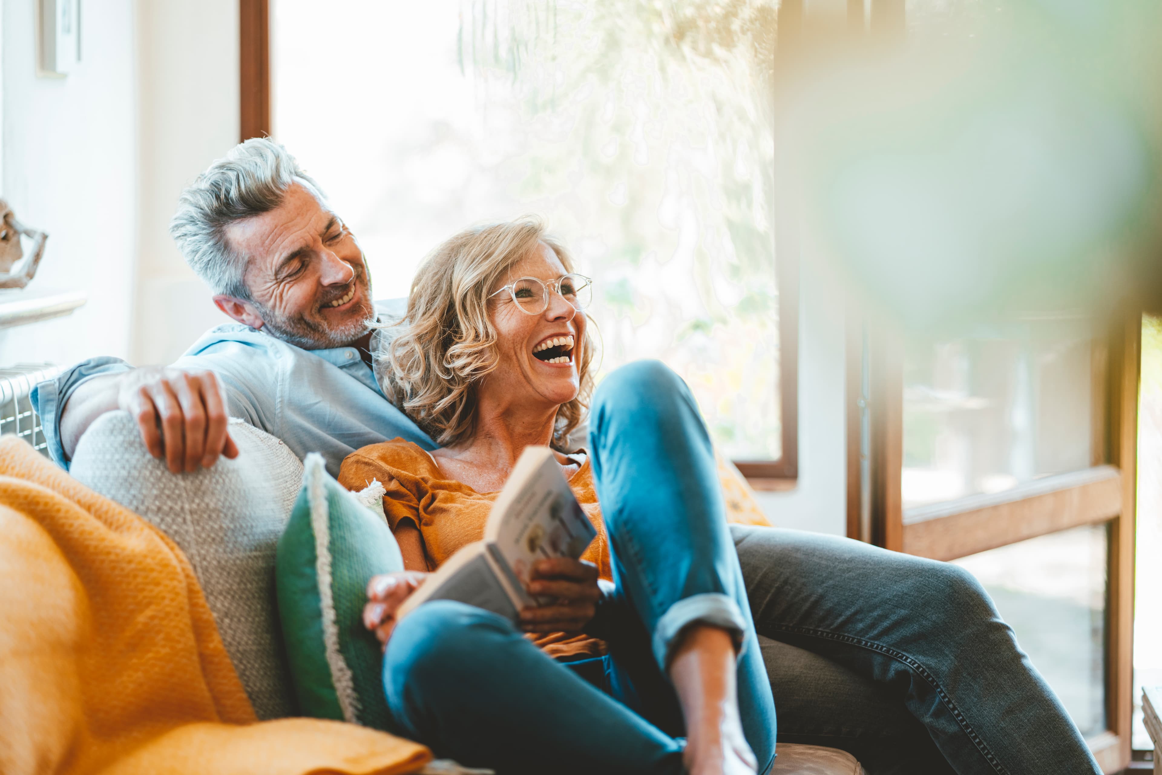 Cheerful mature couple sitting on sofa at home