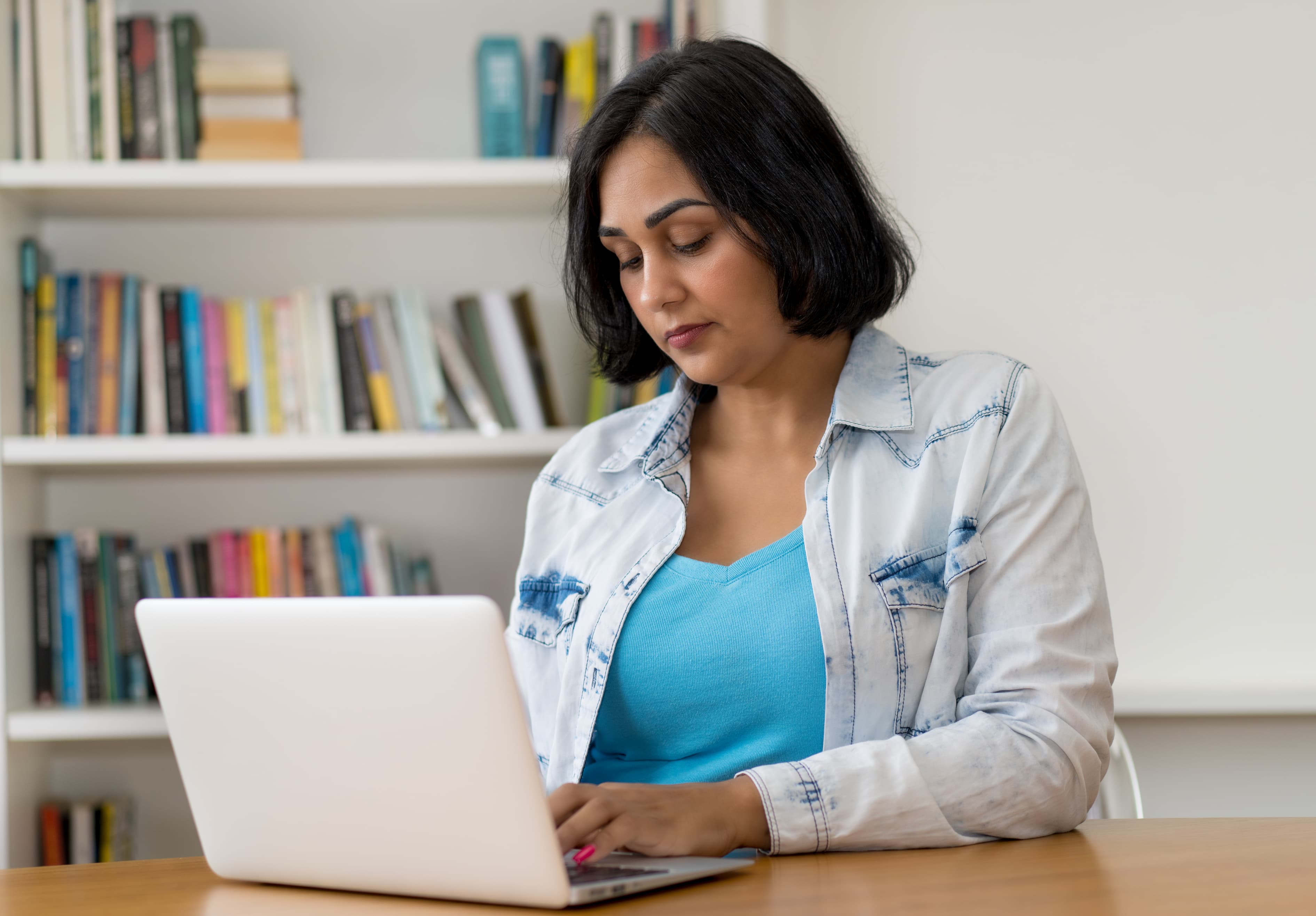 Mexican mature adult woman working with concentration at computer at home