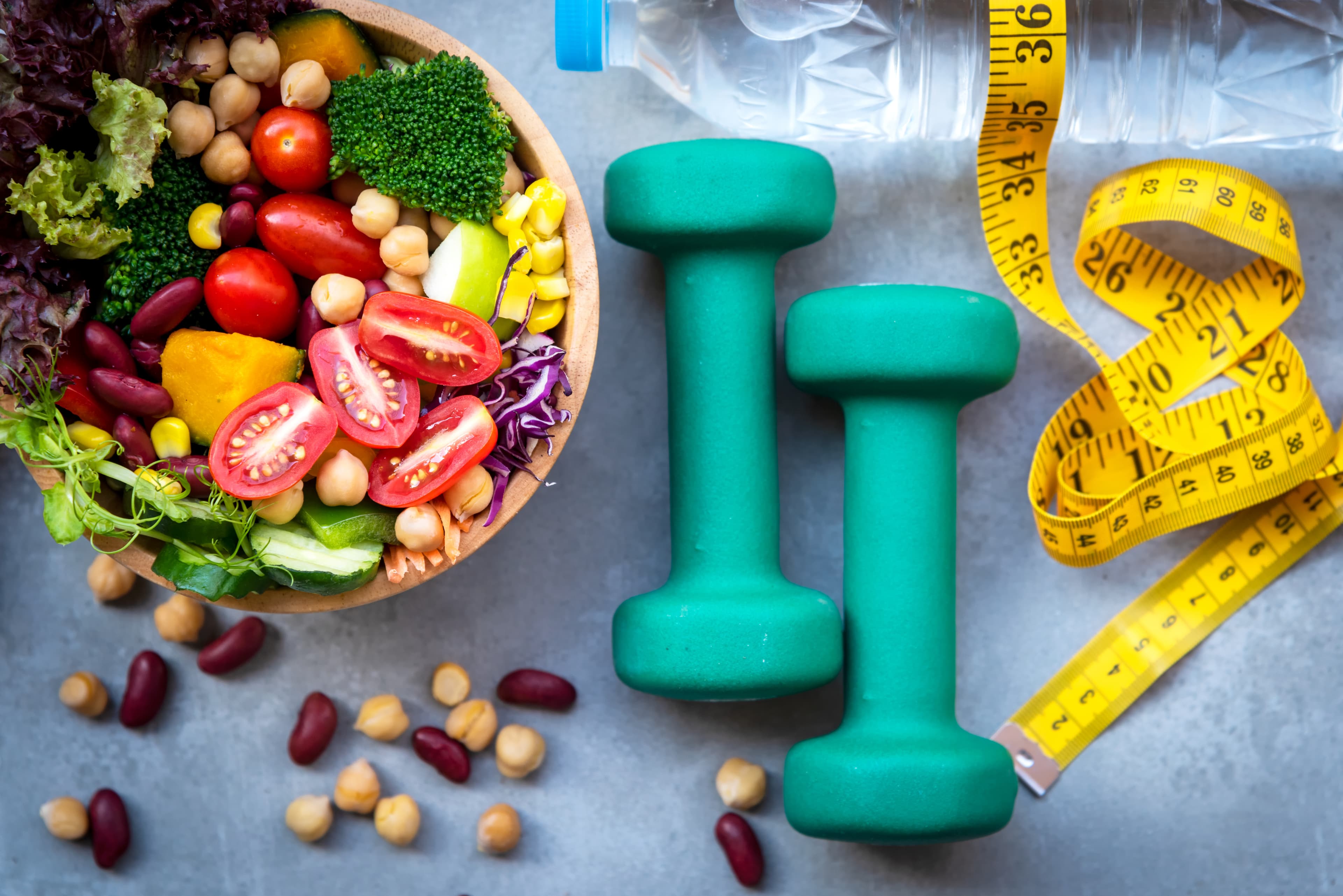 Fresh vegetable salad and healthy food for sport equipment for women diet slimming with measure tap for weight loss on wood background. Healthy Sport Concept.