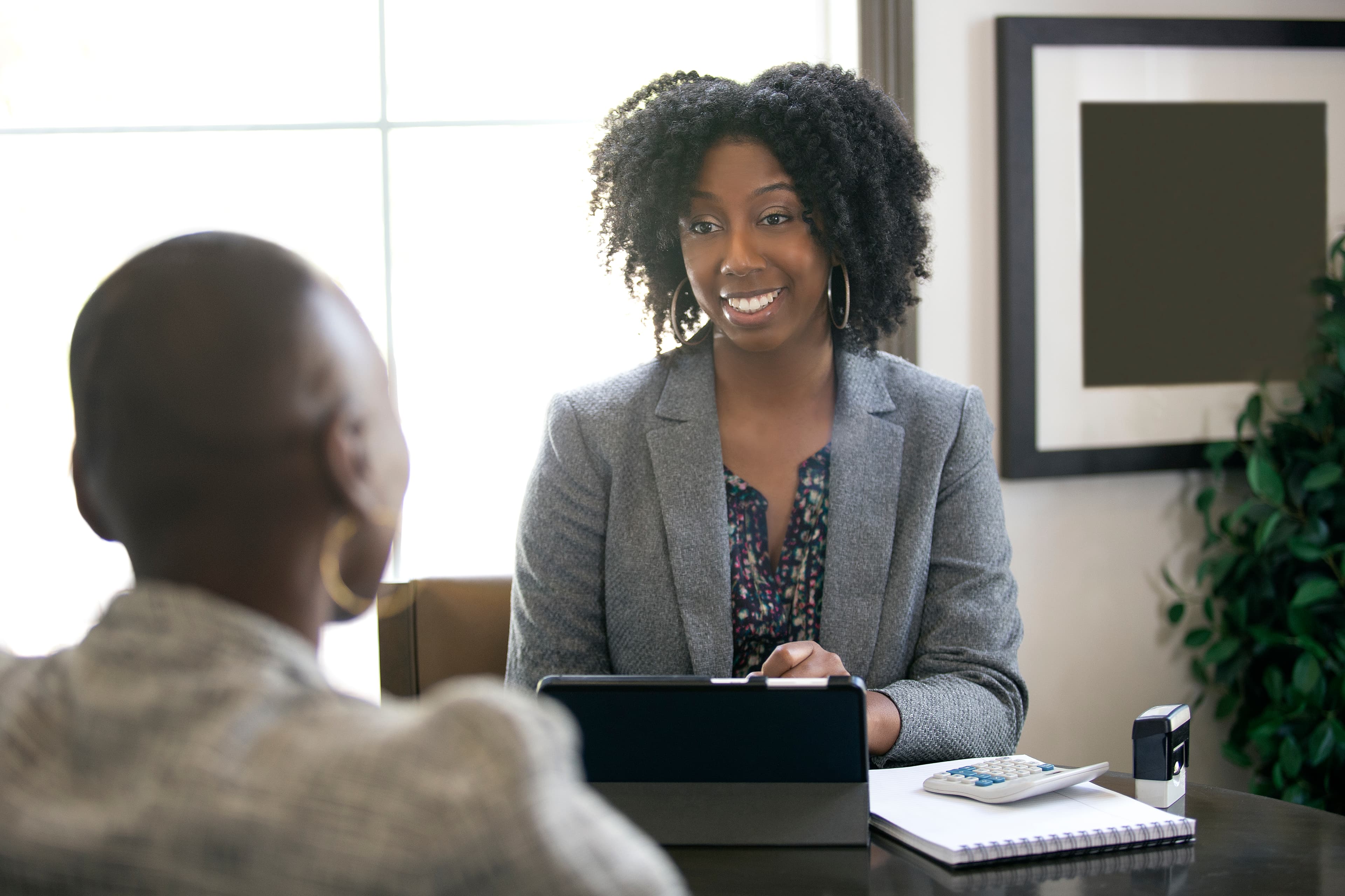 Black female businesswoman in an office with a client giving legal advice about taxes or financial loans. The woman could be a lawyer or a cpa accountant.