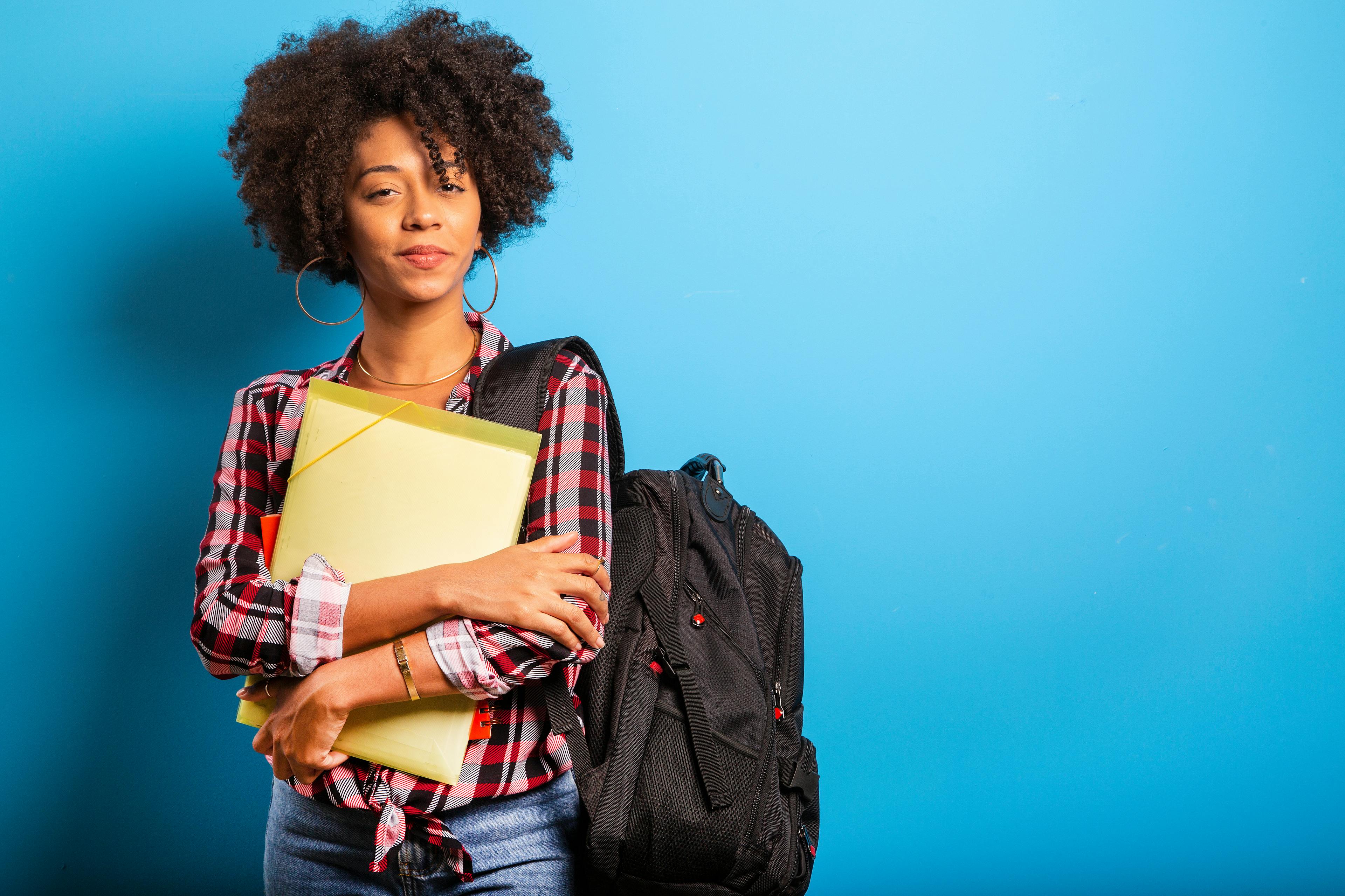 young african student with backpack on the back on blue background.
