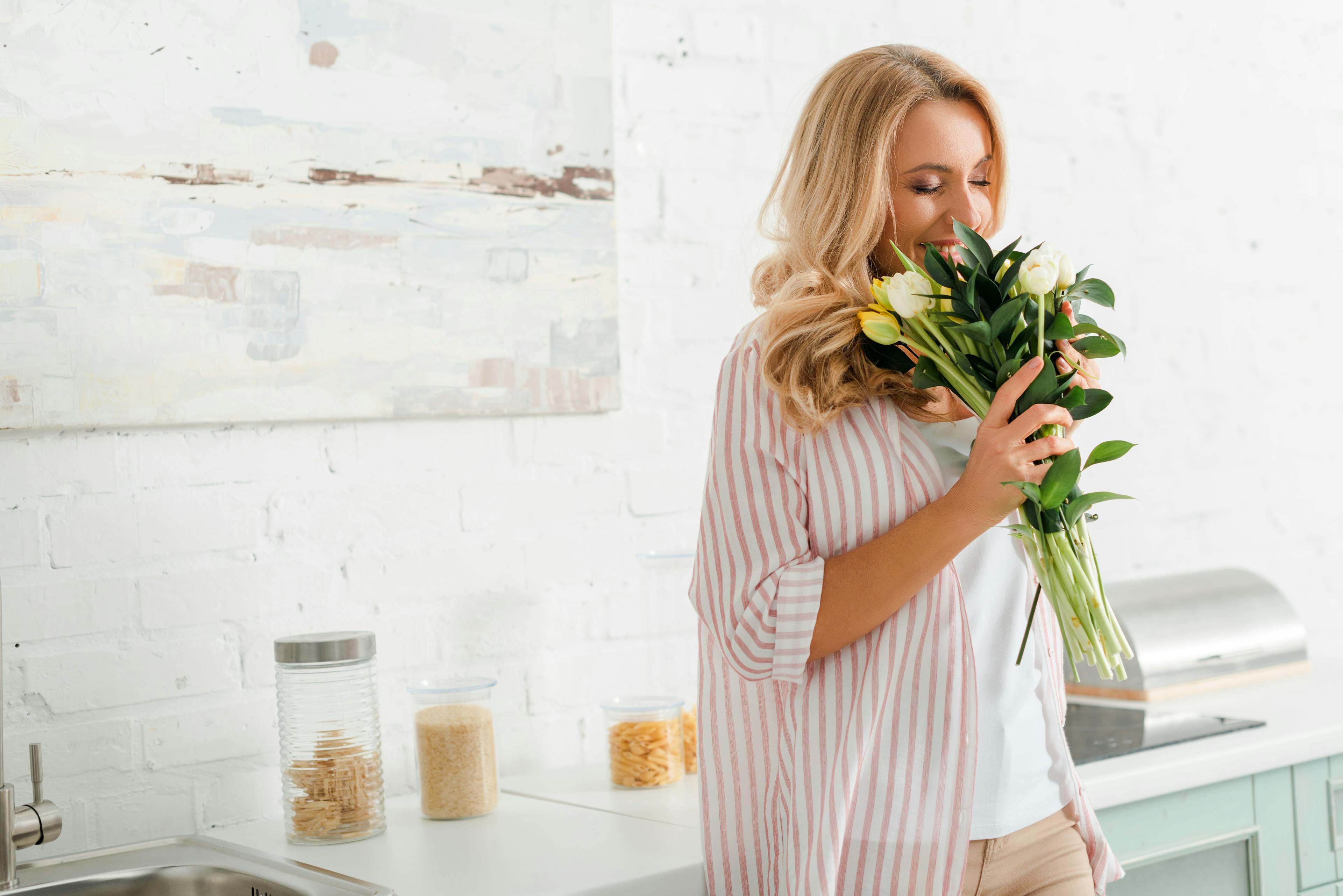 happy woman smelling bouquet of tulips at home