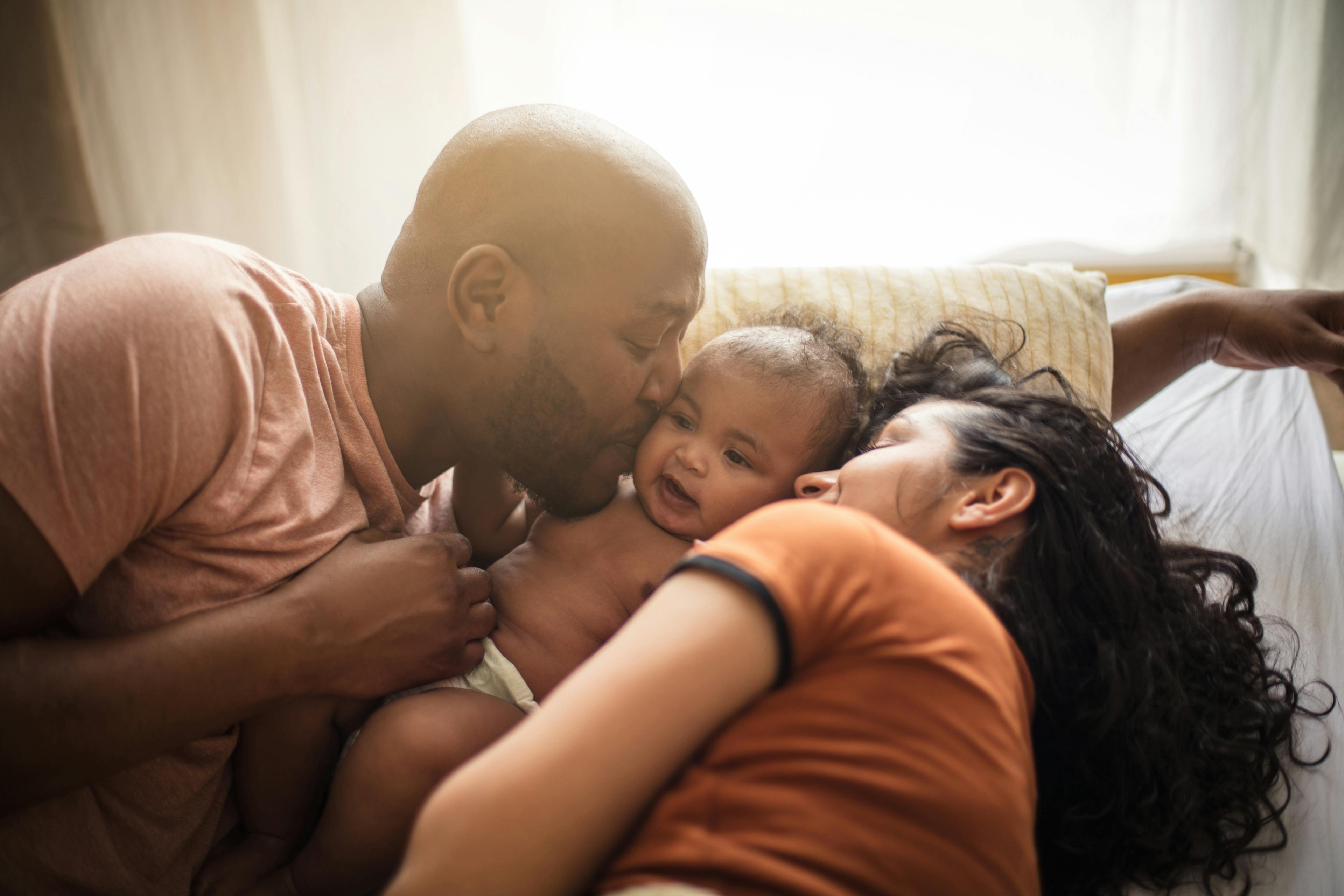 We stick together. African American parents with daughter on bed.