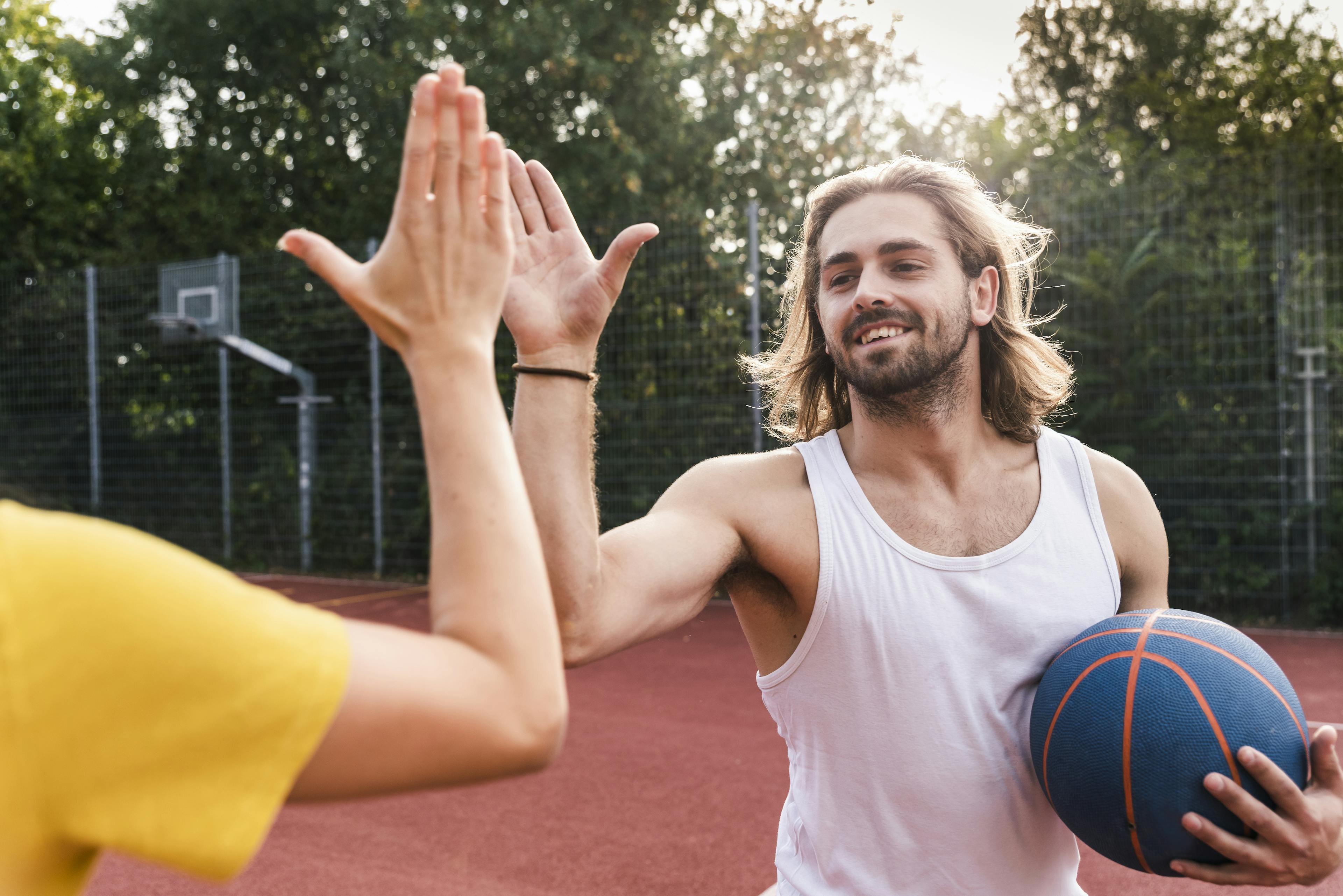 Young man and young woman high-fiving after basketball game