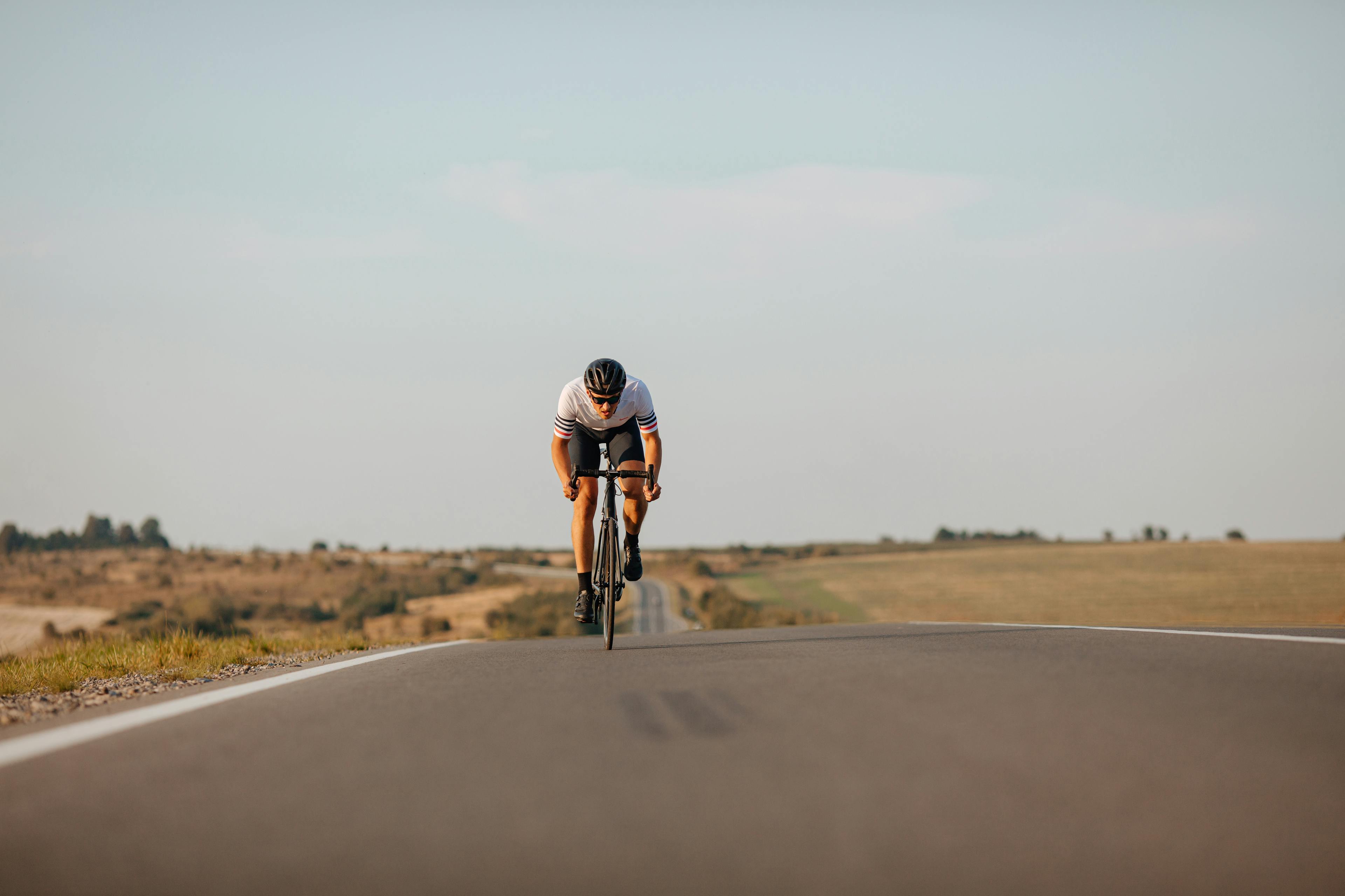 Healthy young man in sport clothing, protective helmet and glasses cycling on asphalt road. Natural landscape. Sport activity on fresh air.