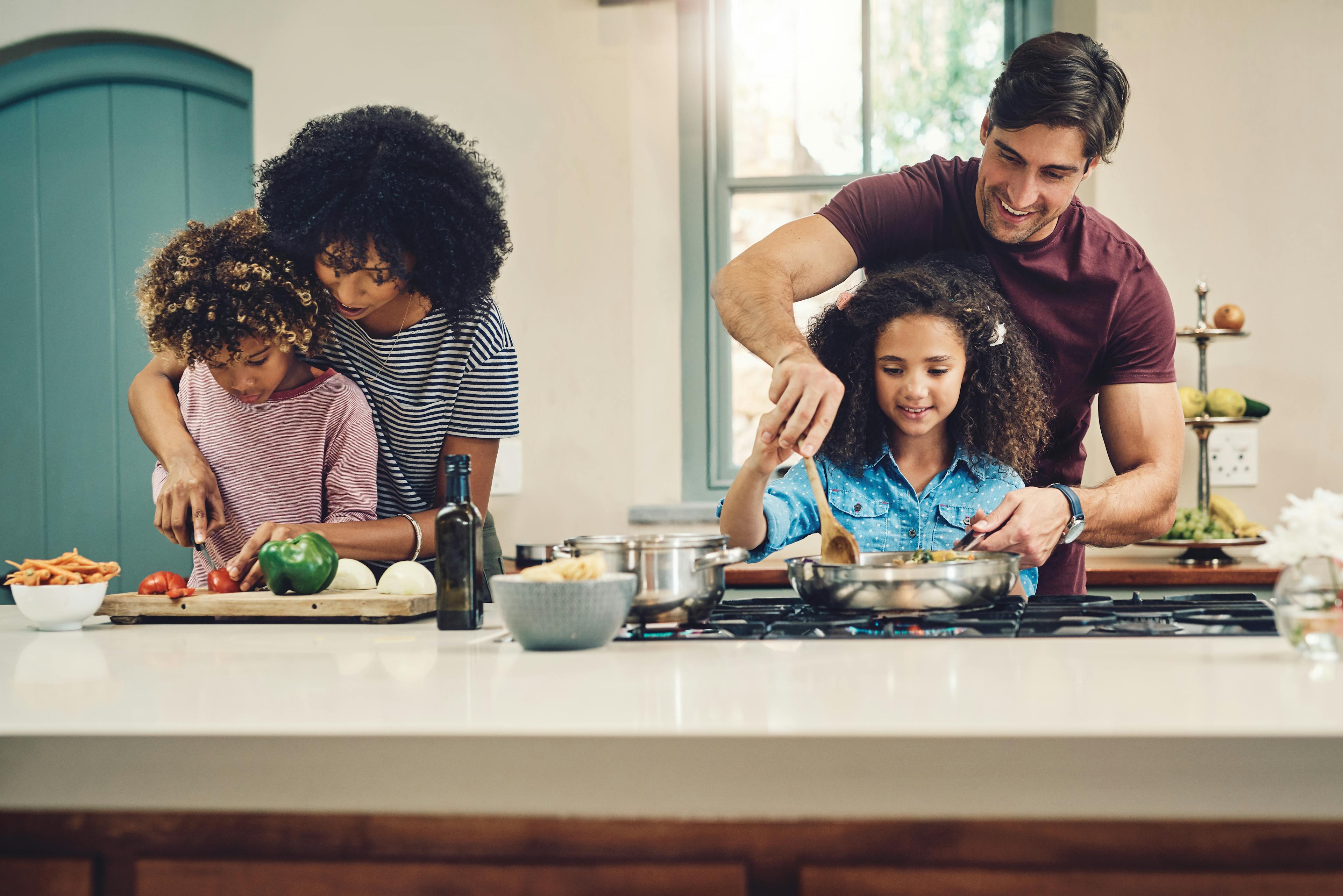 Shot of a family of four cooking together in their kitchen at home