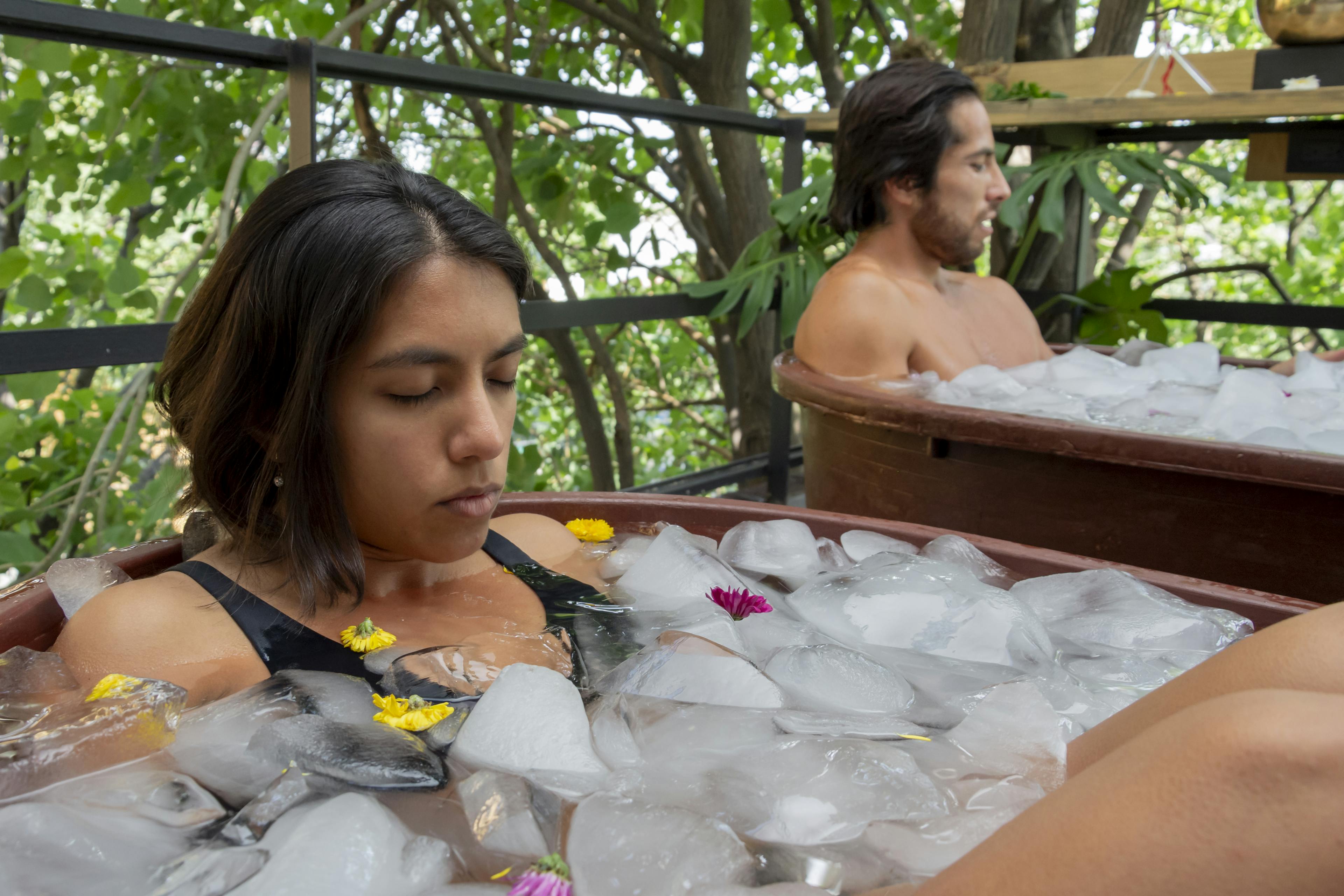 A man and a woman are taking an ice bath in a tub on the outdoor terrace