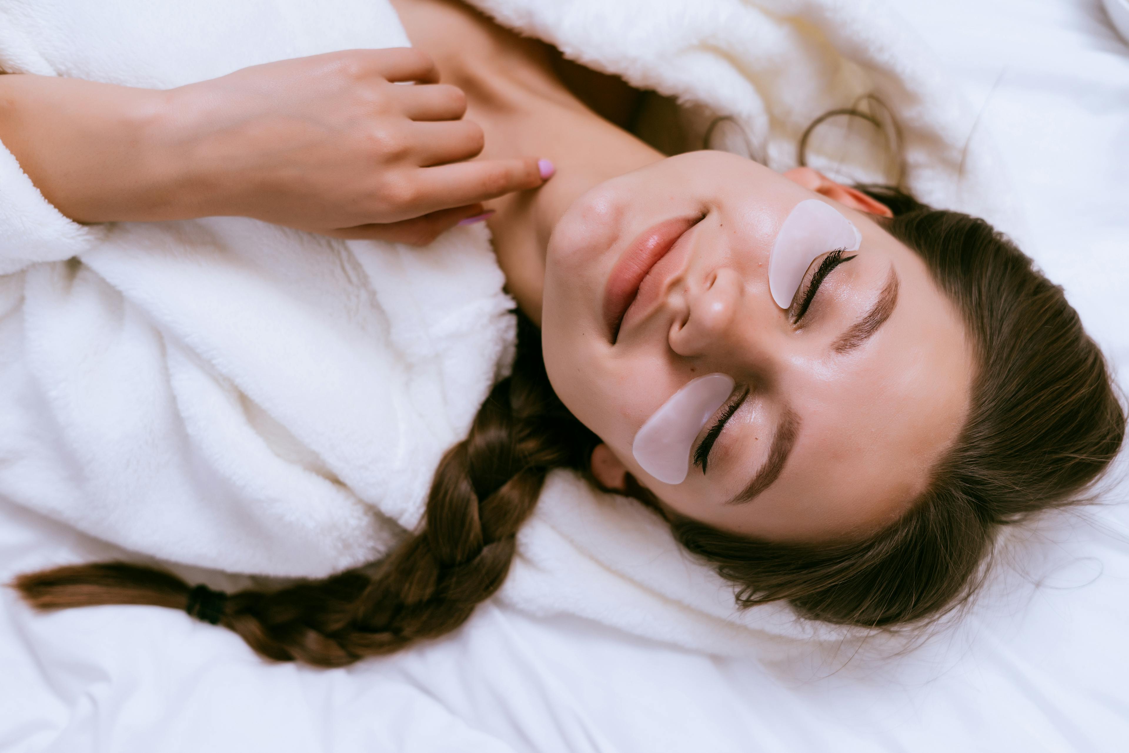smiling happy girl lies in bed, under eyes white patches, eyes closed