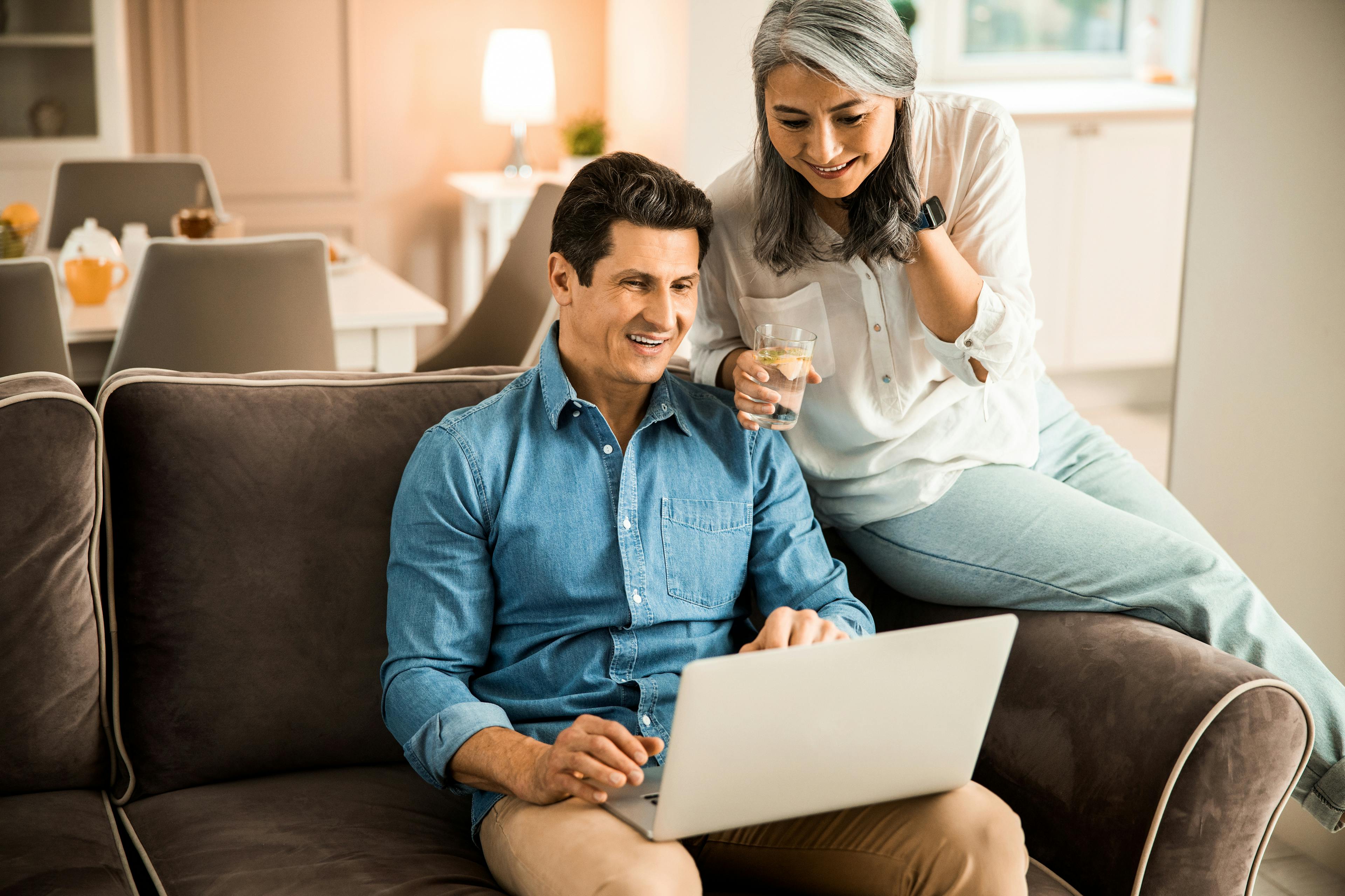 Happy adult man working with laptop while his wife sitting next to him stock photo