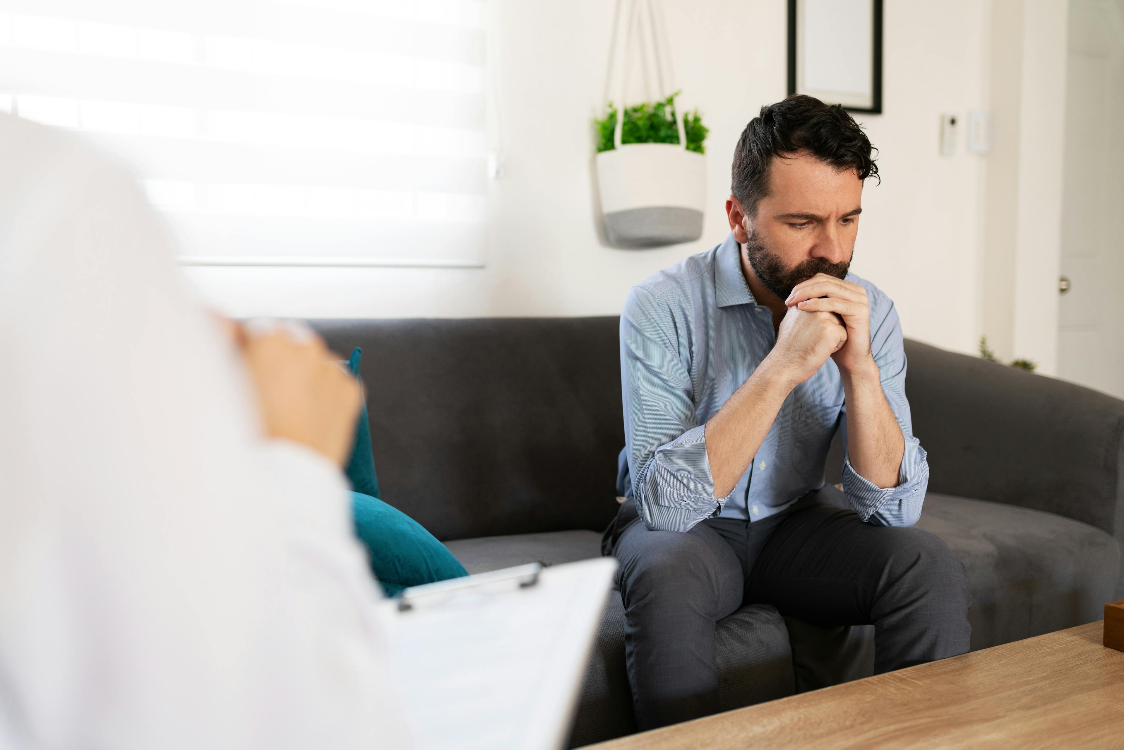 Hispanic adult man with depression and anxiety listening to the professional advice of his female psychiatrist