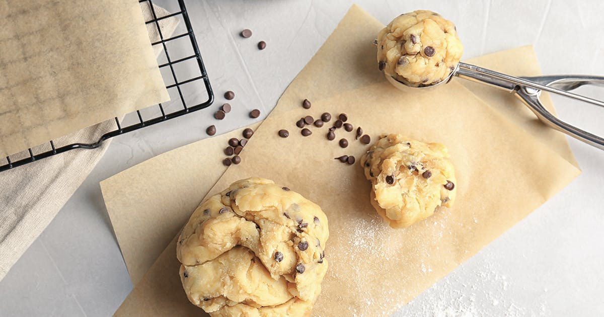 Raw cookie dough and chocolate chips on a piece of parchment paper.