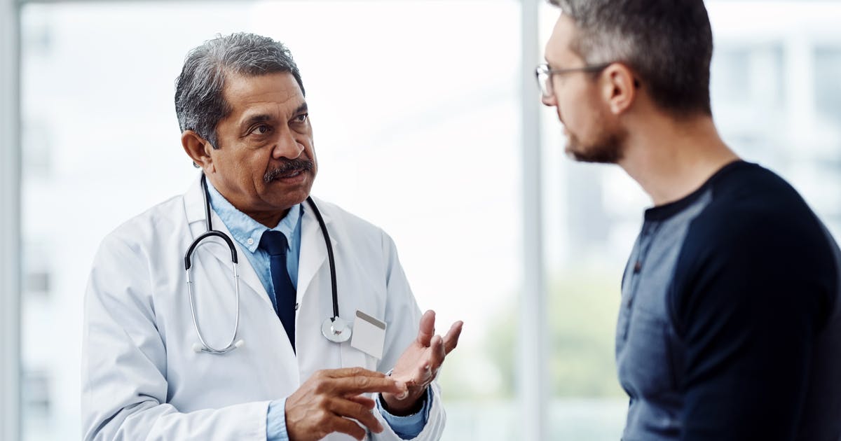 A doctor gestures as he talks to a patient