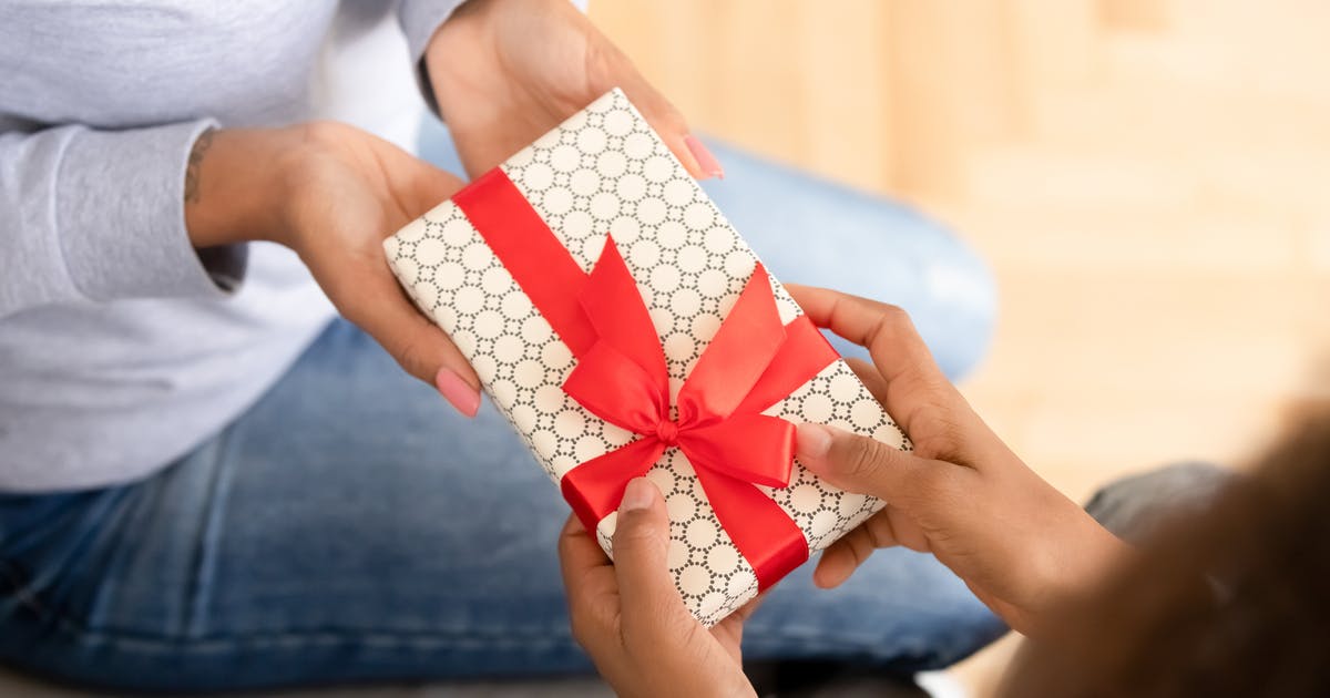 Two sets of hands exchanging a small, wrapped gift.