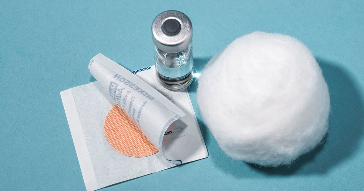 A bandage, a vial of vaccine and a cotton ball.