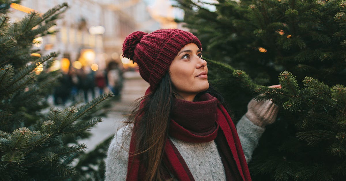 A young woman shopping for a Christmas tree alone.