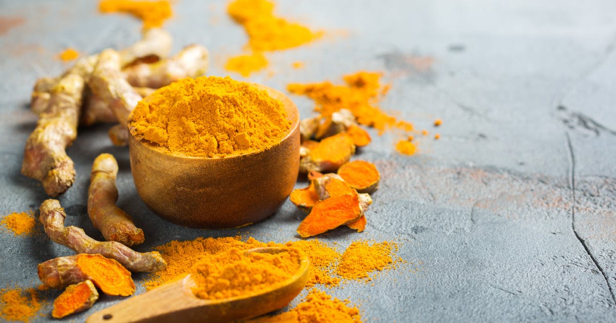 Crushed and whole turmeric and a wooden spoon