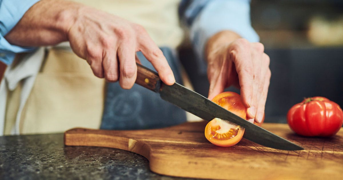 A man slicing a yellow tomato.