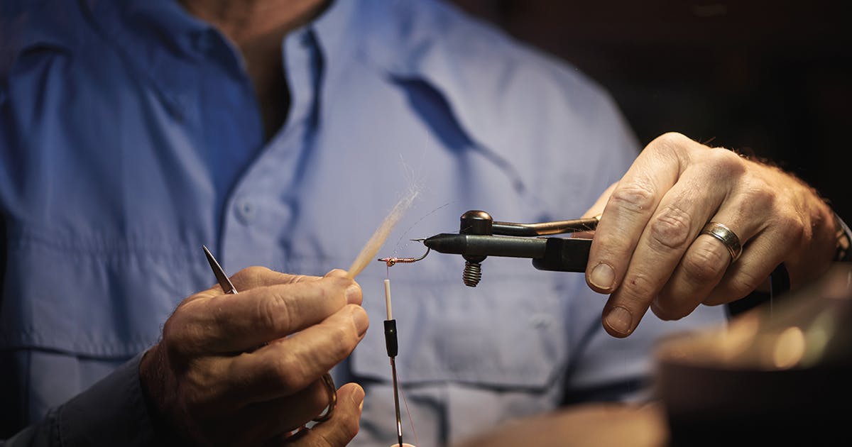 An older man tying a fly for fly fishing.
