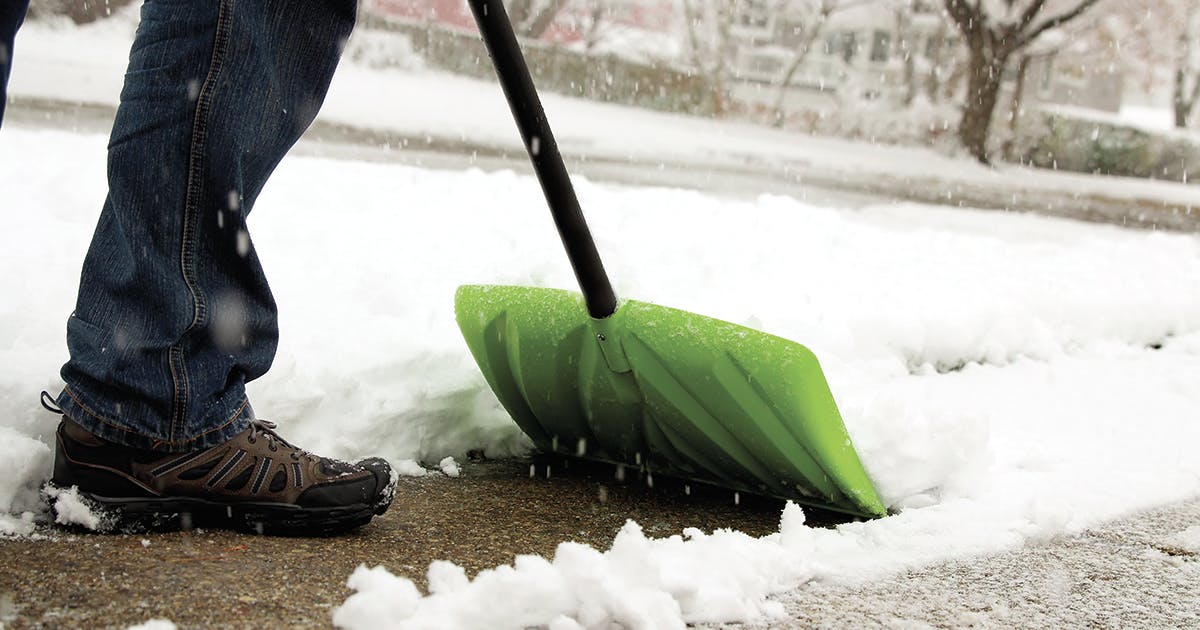 A person shoveling snow from a sidewalk.