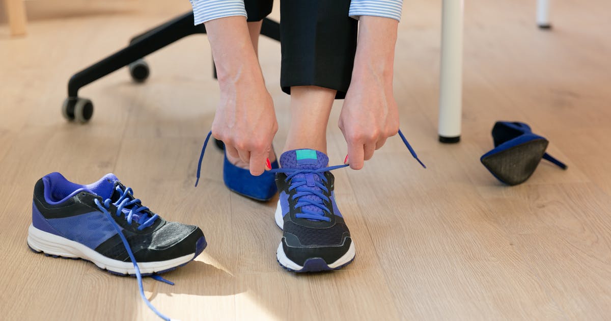 A woman swaps heels for walking shoes in an office setting.