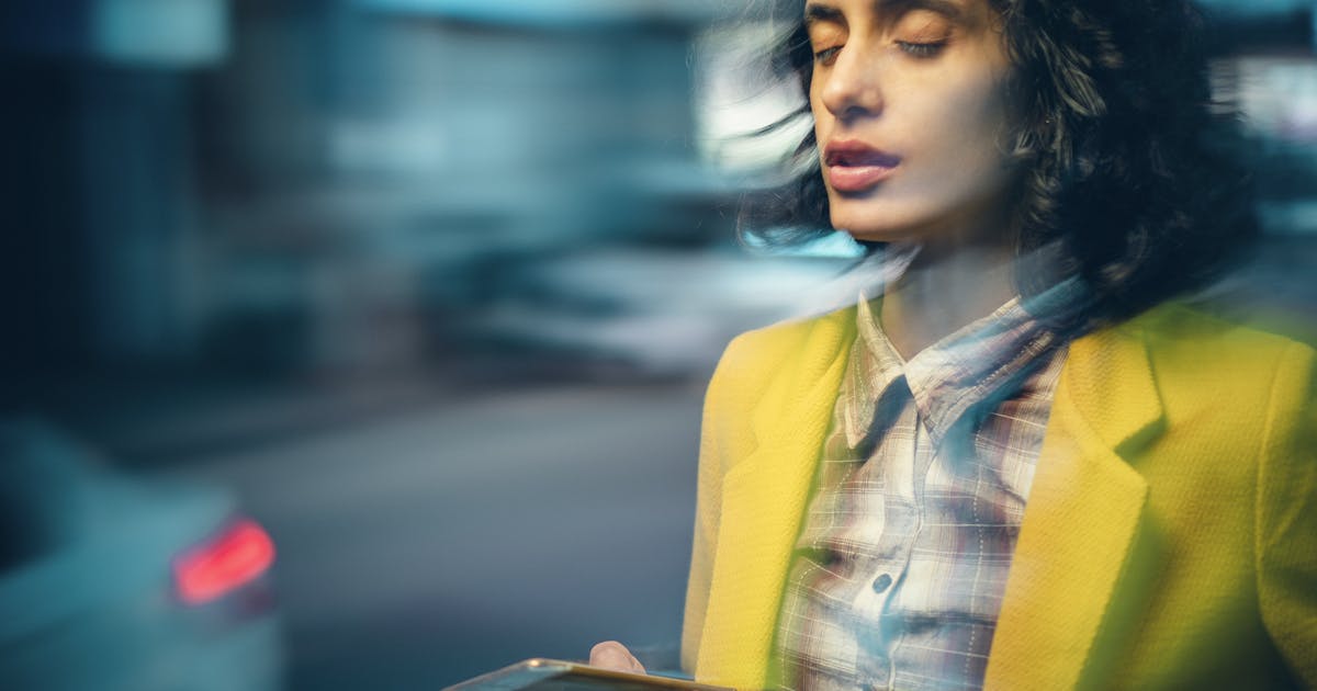A woman holds a phone; The image is blurred to imply vertigo