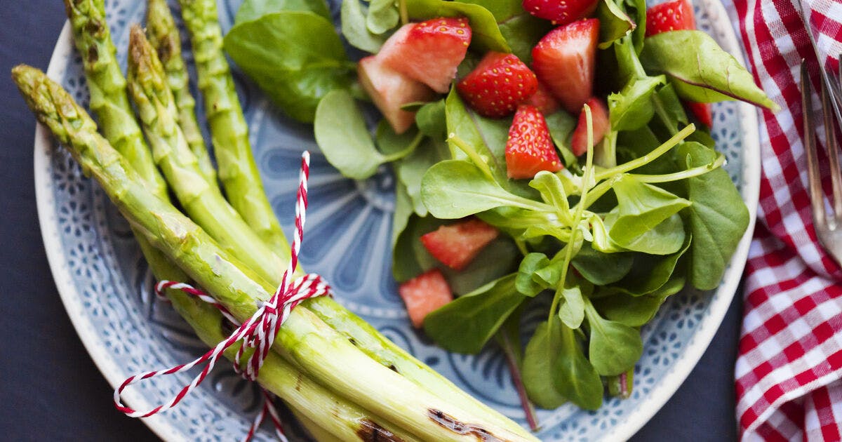 Asparagus, strawberries and spinach on a plate.
