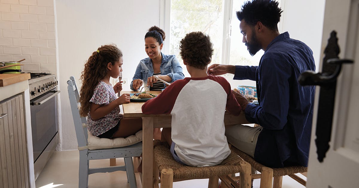 A family of four shares a meal at their kitchen table.