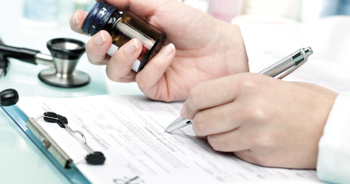 A doctor writing on a prescription pad.