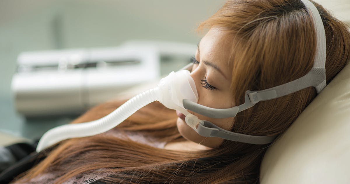 A woman wears a CPAP mask while sleeping. 
