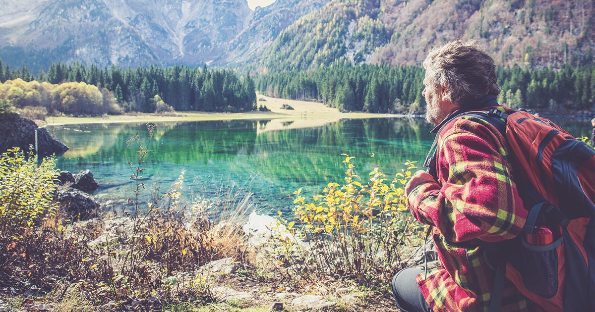 A hiker sits beside a mountain lake. 