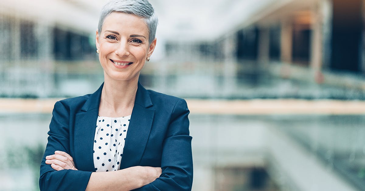  Smiling woman in business attire stands with arms crossed