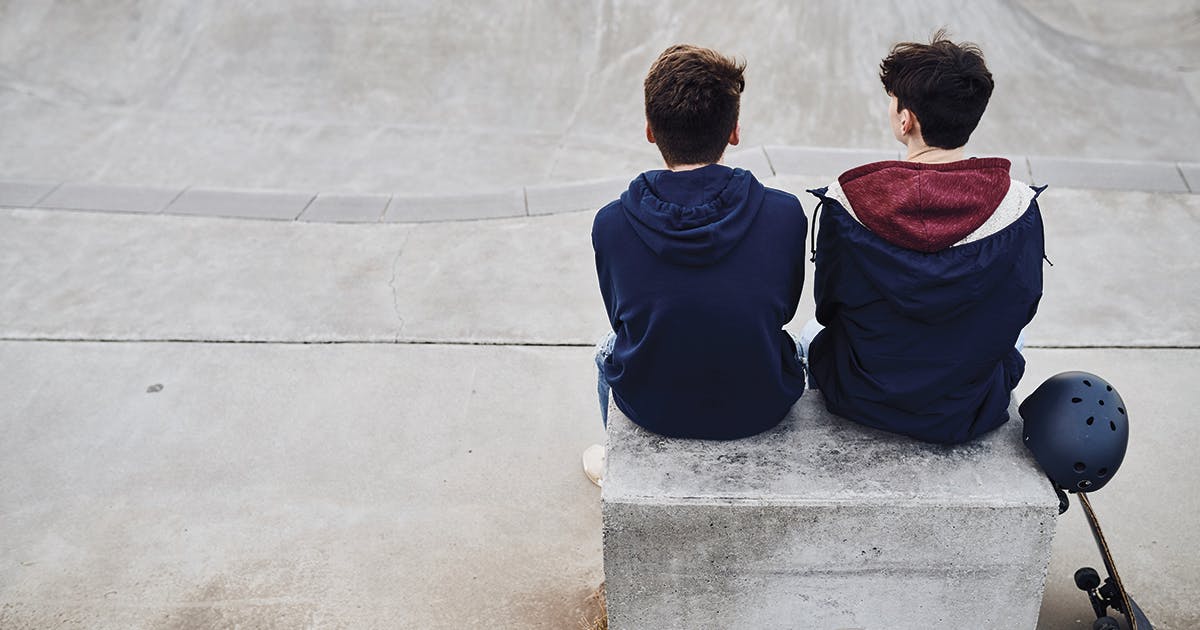 Two teenage boys sitting on a bench.
