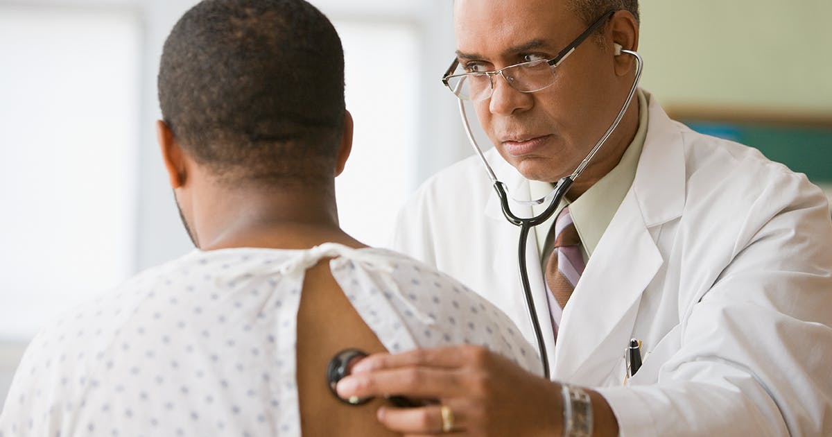 A doctor is using a stethoscope to listen to a man's lungs.