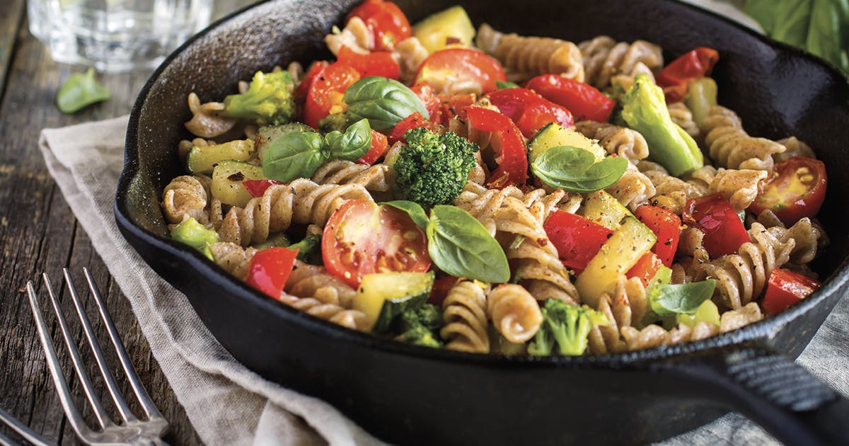 A cast iron skillet filled with pasta and vegetables.