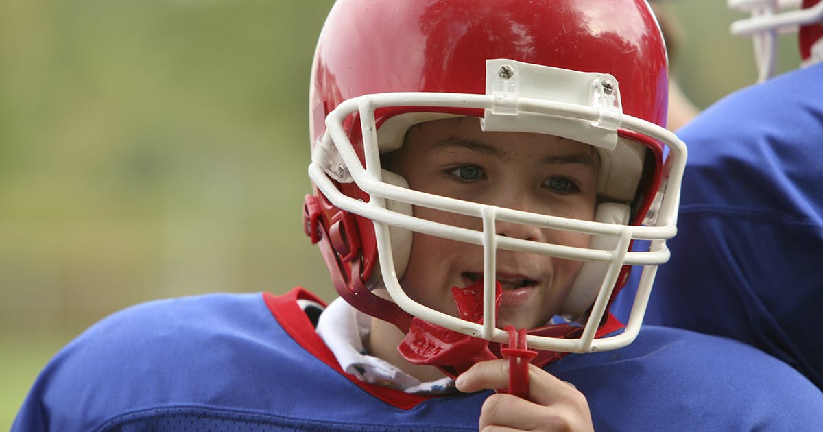 Boy in a football helmet and uniform. 