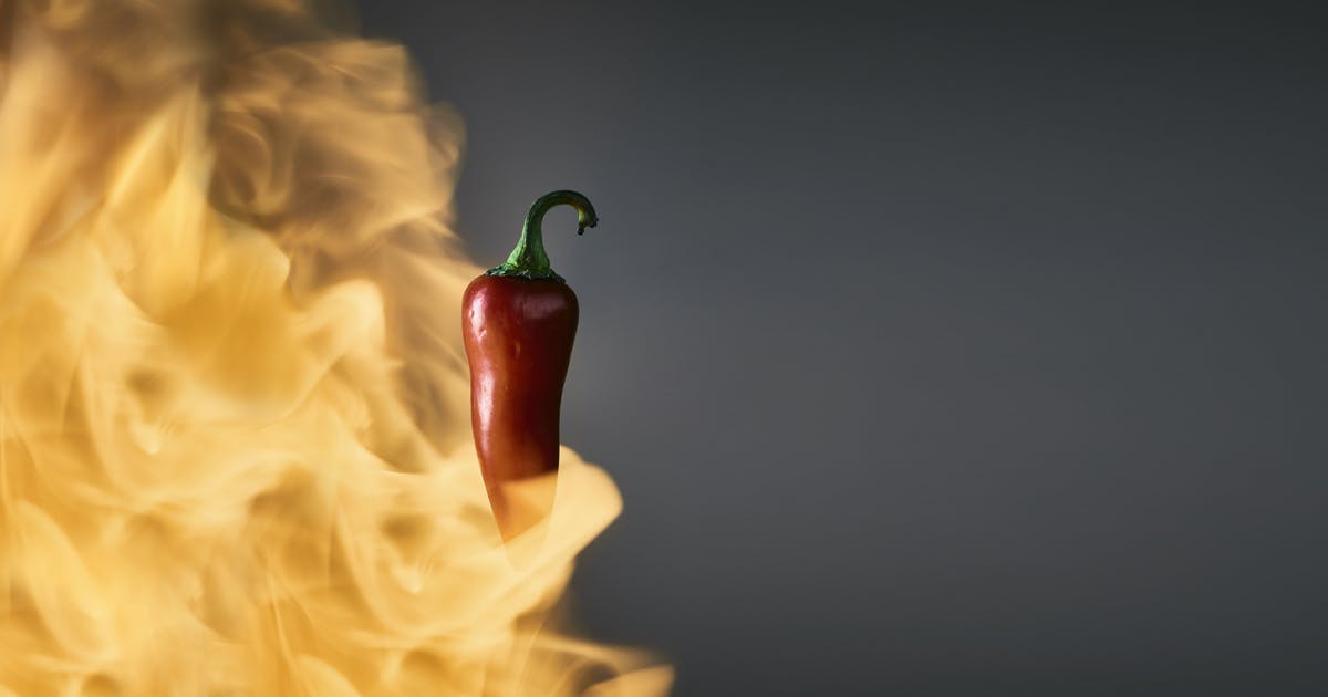 Flames burst around a chile pepper.