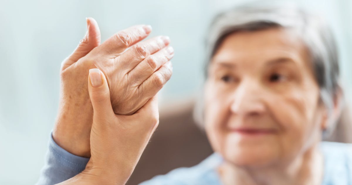 Someone holds an older woman's hand