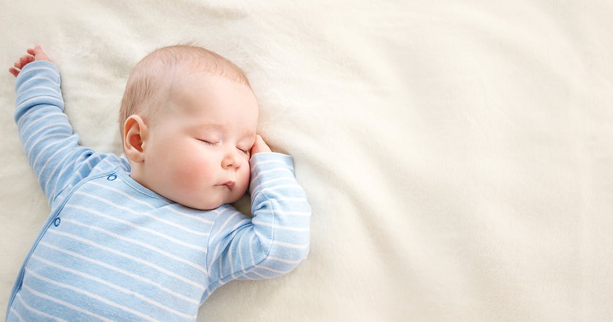 A sleeping baby in a blue onesie.