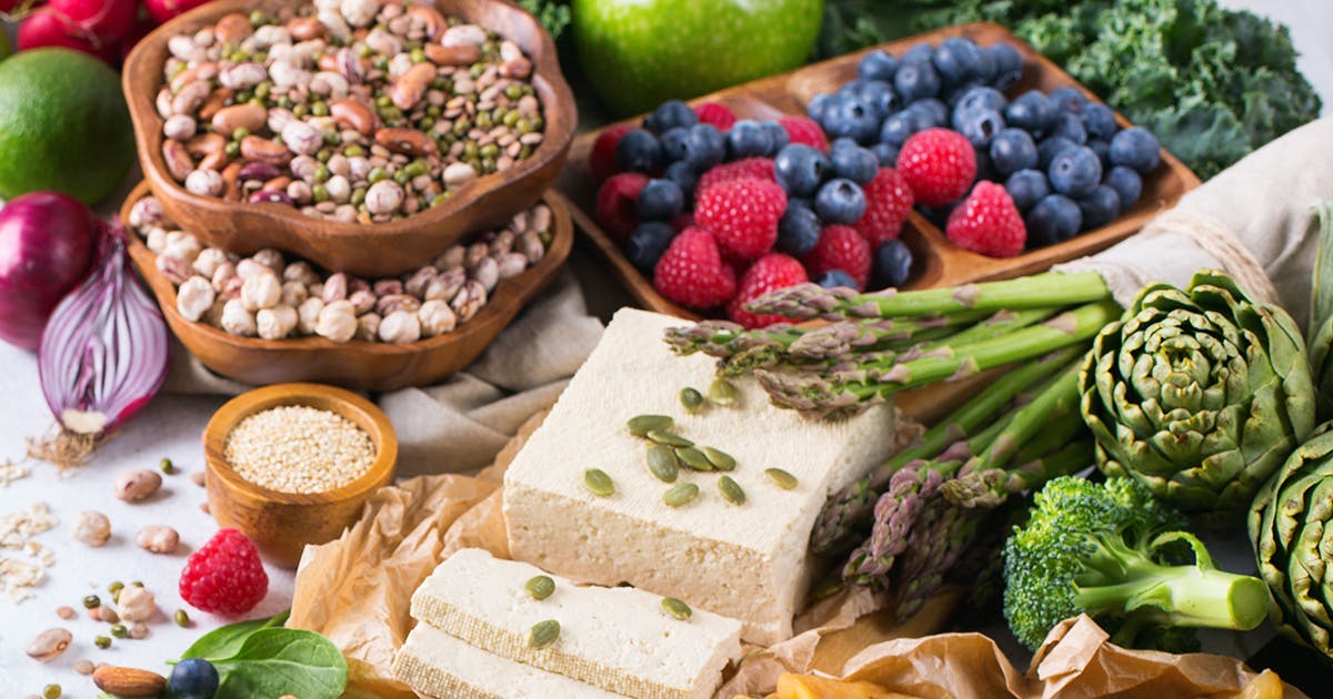 A spread of colorful foods, including berries, nuts and seeds, vegetables, and cheese.