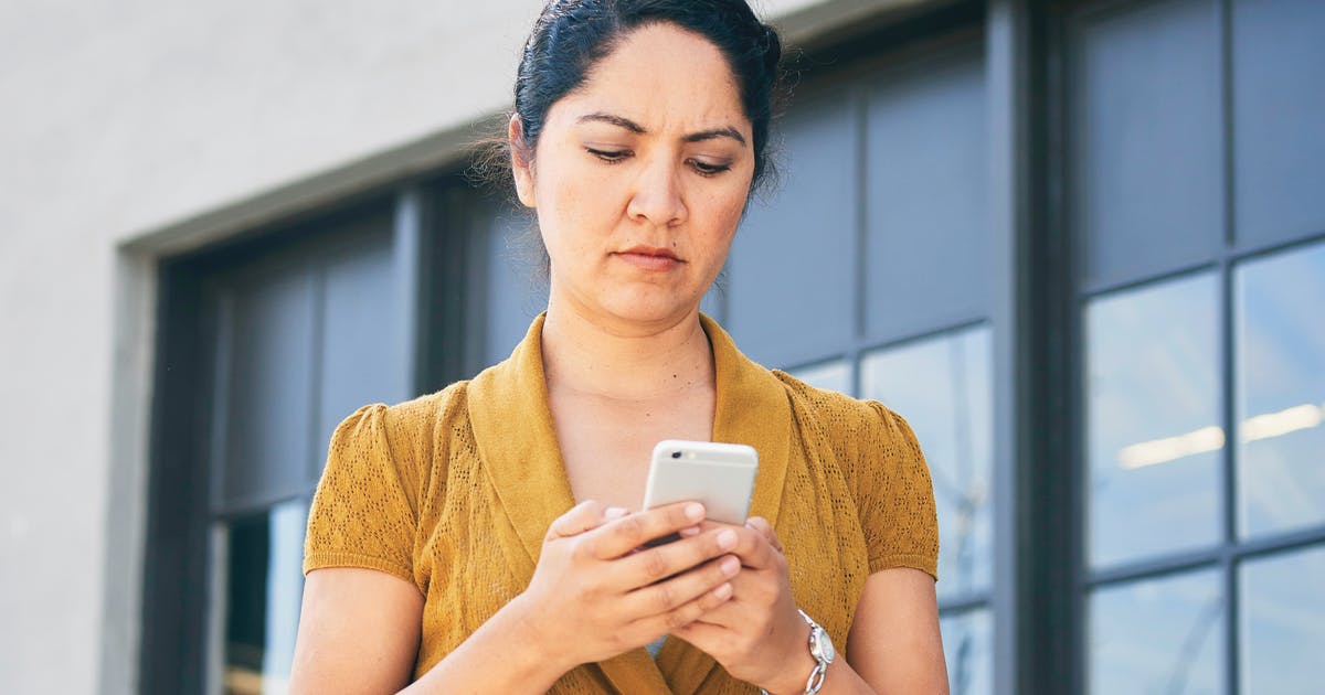 A woman with a worried expression checks her phone.
