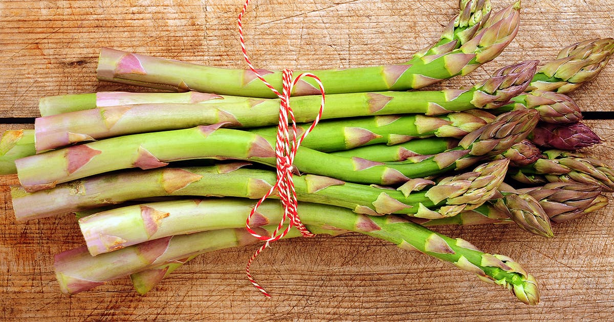 A bunch of asparagus tied with red and white string.