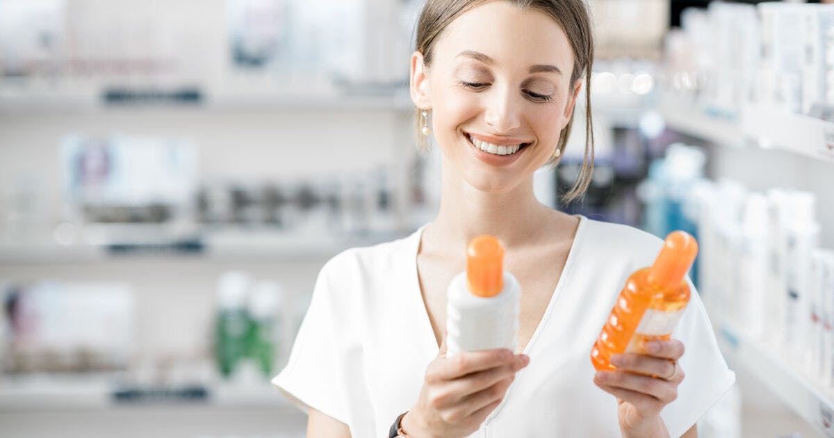   A woman comparing two bottles in a drugstore