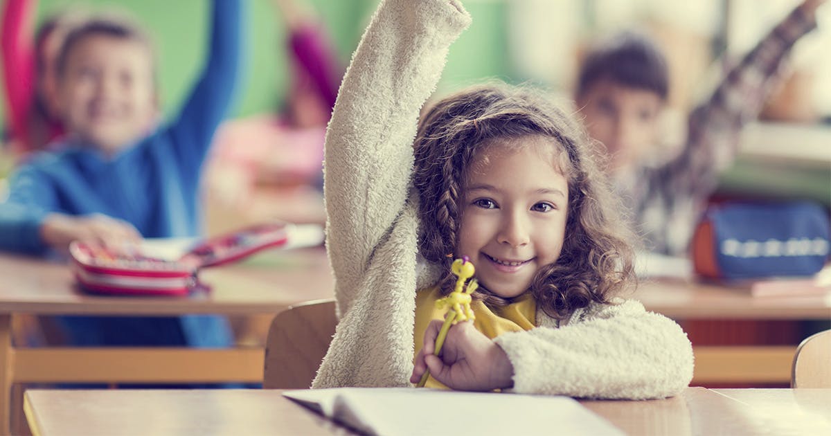 Grade-schooler raises her hand in a classroom.