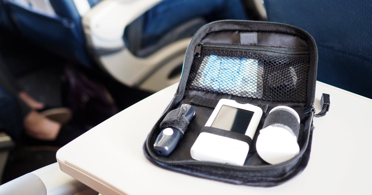 A kit of diabetes supplies on the seat-back table of an airplane