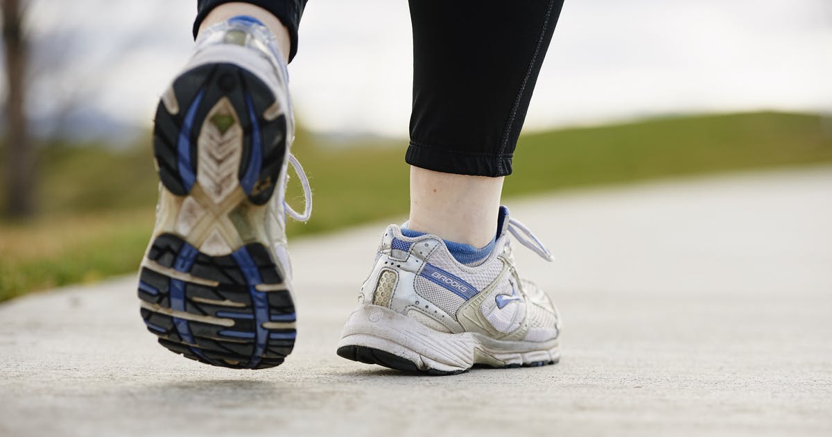 A woman's feet walking away, wearing athletic shoes.