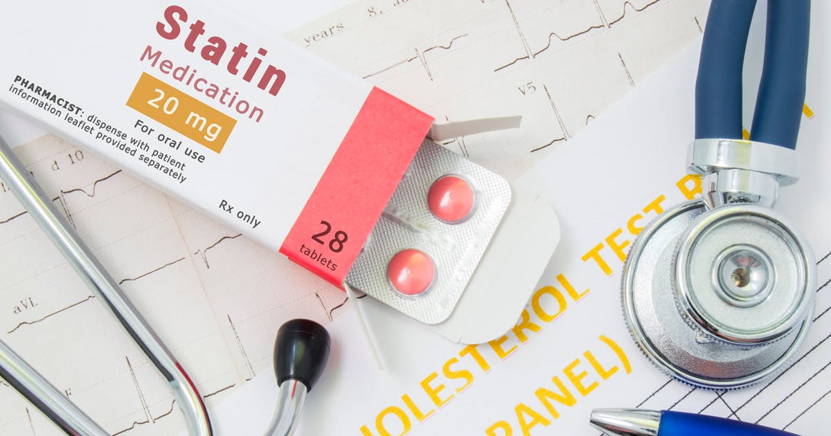 An open box of statin medication, alongside a stethoscope, a pen and printouts of lab test results.
