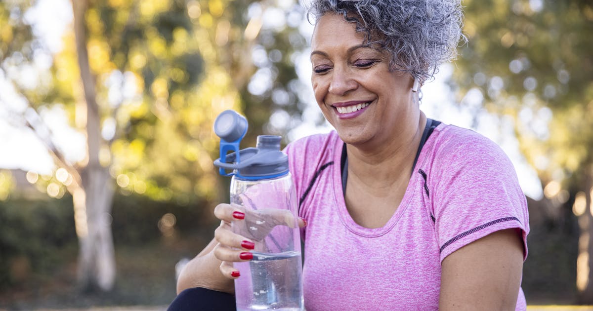 A woman drinks from a reusable water bottle.